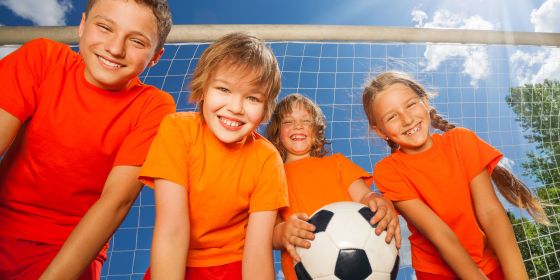 Kids In Orange Shirts Standing In Front Of Soccer Goals